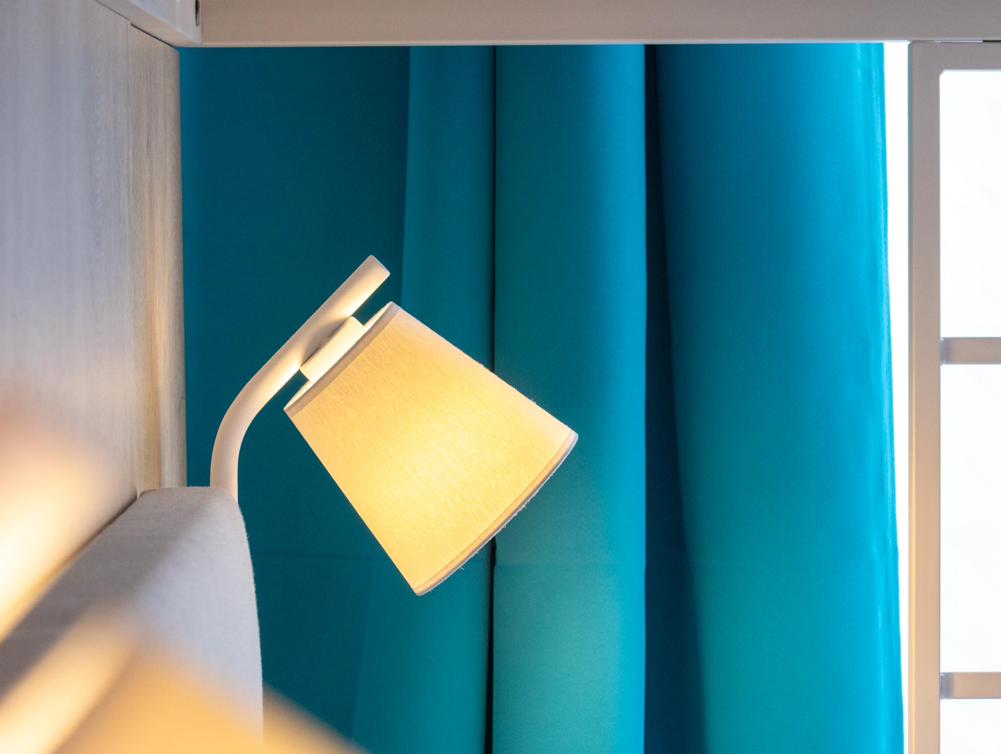 Leselampe mit Teal-Vorhang im FairSchlafen Boutique Hotel Neustadt in Holstein